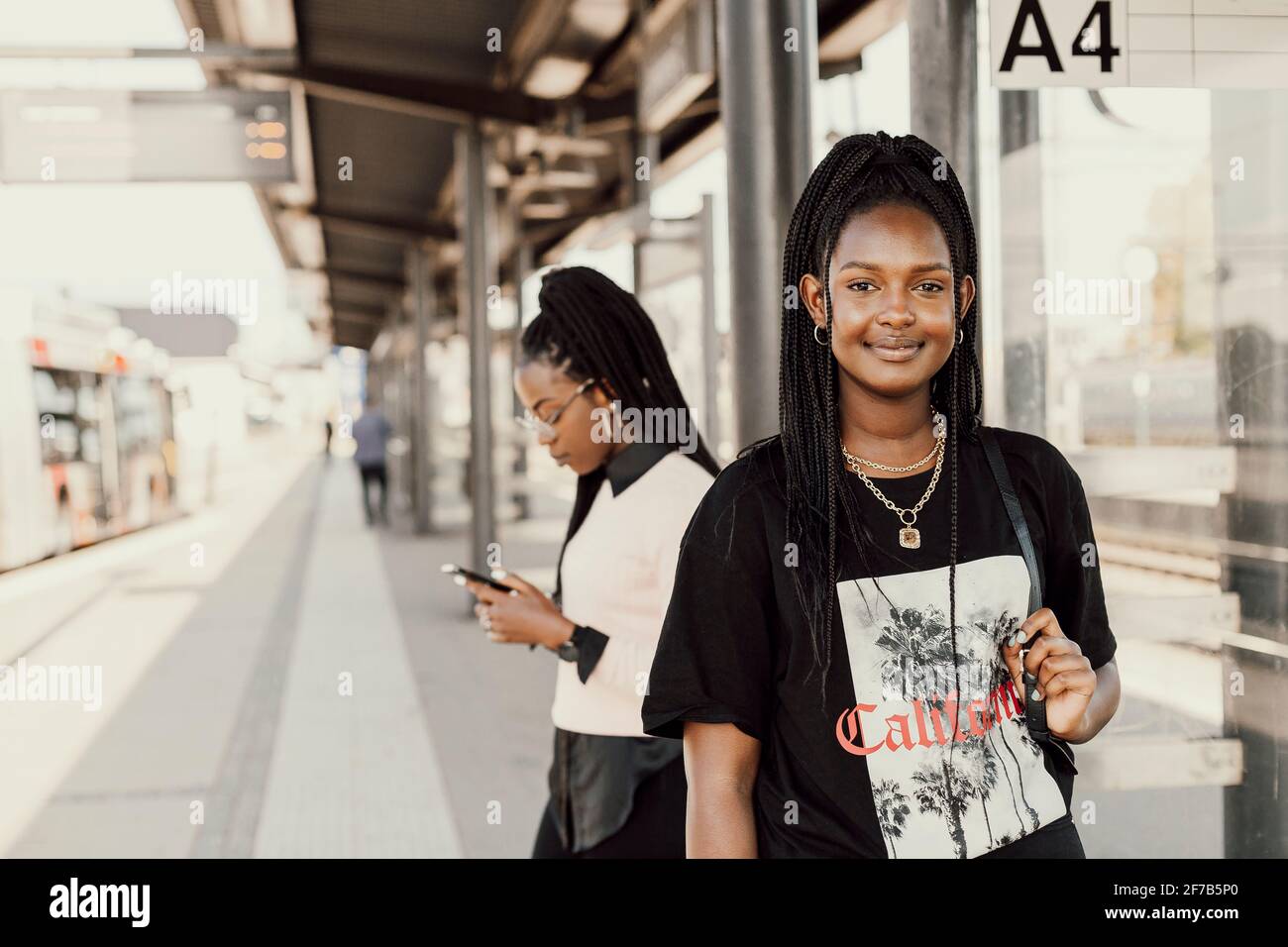 Lächelnde Frauen stehen am Bahnhofsplatz Stockfoto