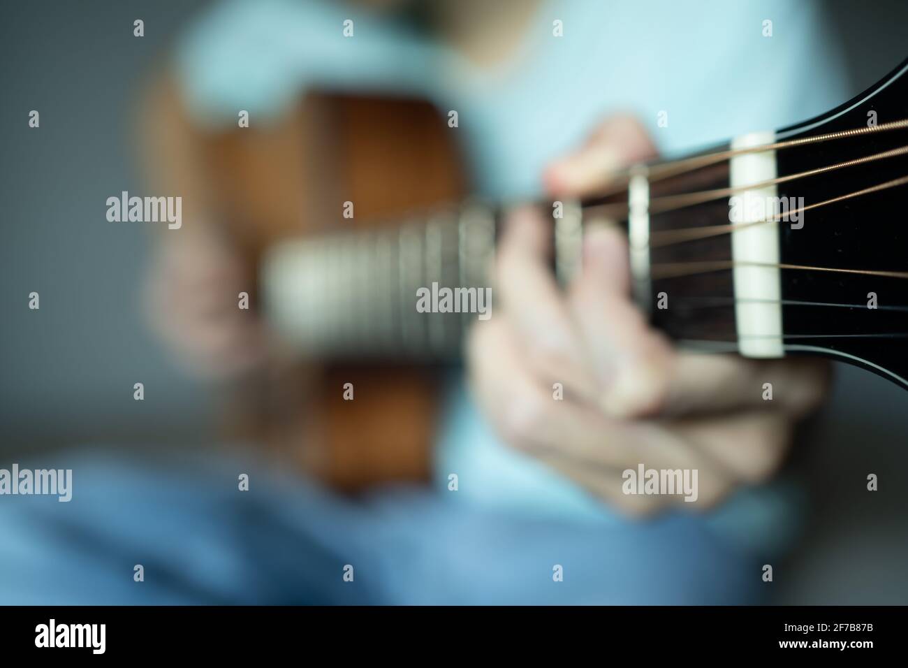 Verschwommenes Foto eines Mannes, der als Hintergrund akustische Gitarre spielt Stockfoto