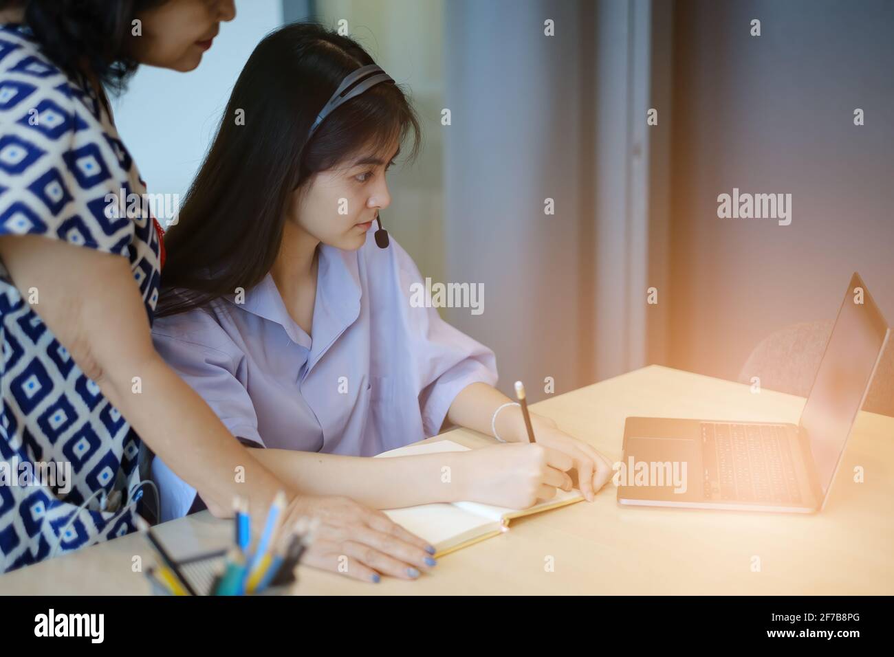 Mutter und Tochter unterrichten und lernen online mit dem Laptop. Erwachsene Frau lehrt Kind die Mathematik. Frohe Familie. Stockfoto