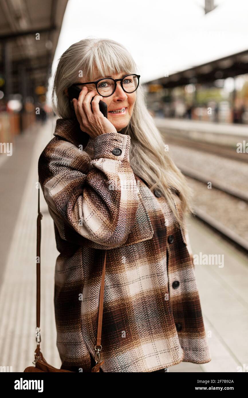 Reife Frau am Telefon am Bahnhof Stockfoto