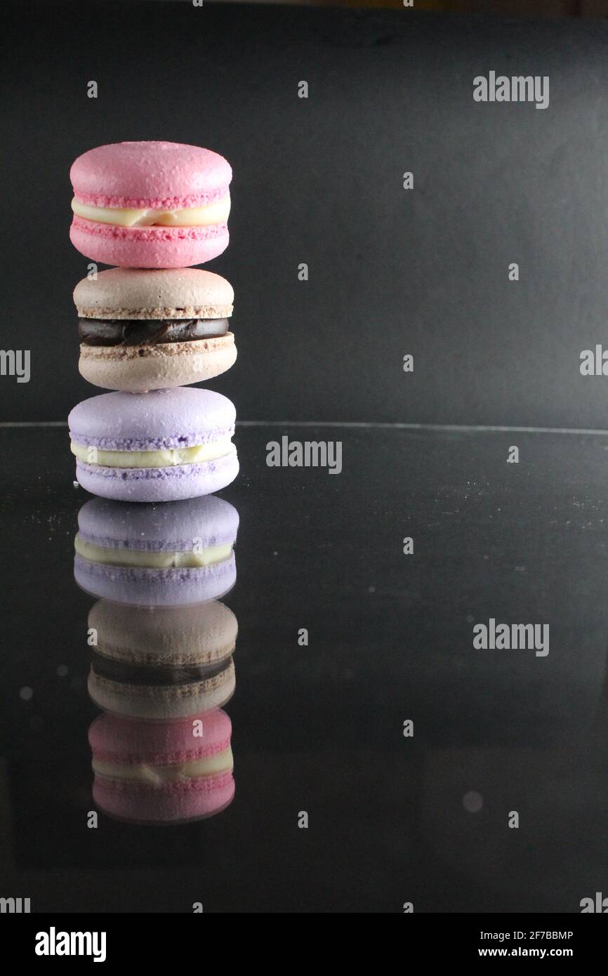 Drei makaronfarbene, braun-pinke Kuchen auf schwarzem, glänzenden Hintergrund mit Platz für Text und Textraum. Stockfoto