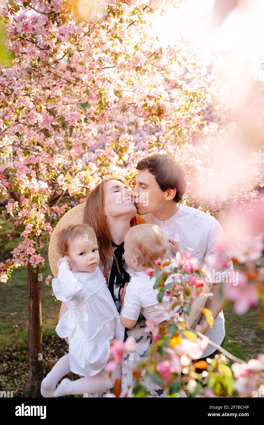 Porträt einer glücklichen und gesunden Familie auf dem Hintergrund eines blühenden Apfelbaums im Garten. Stockfoto