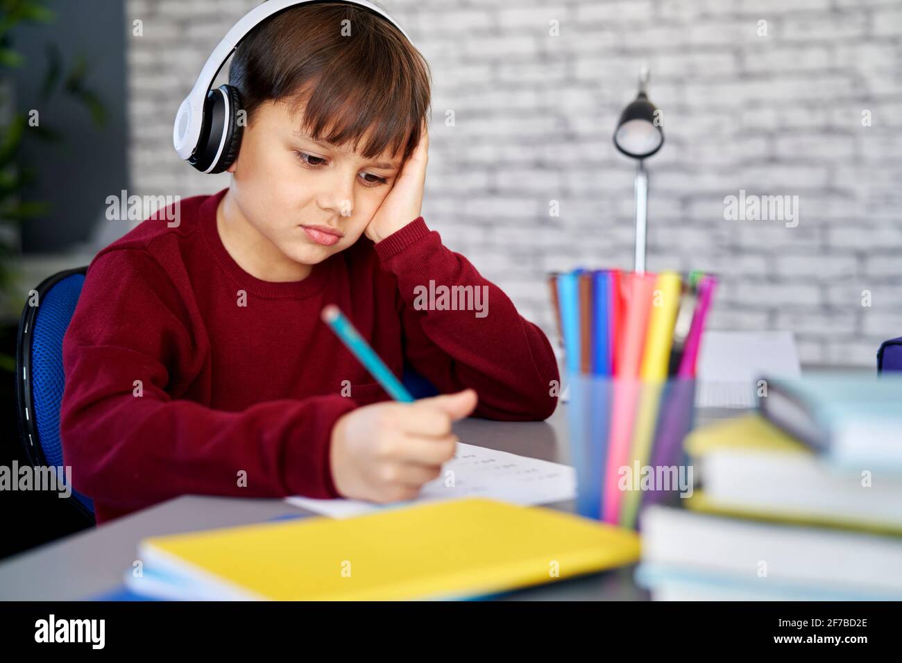 Gelangweilter Schuljunge lernt von zu Hause aus Stockfoto