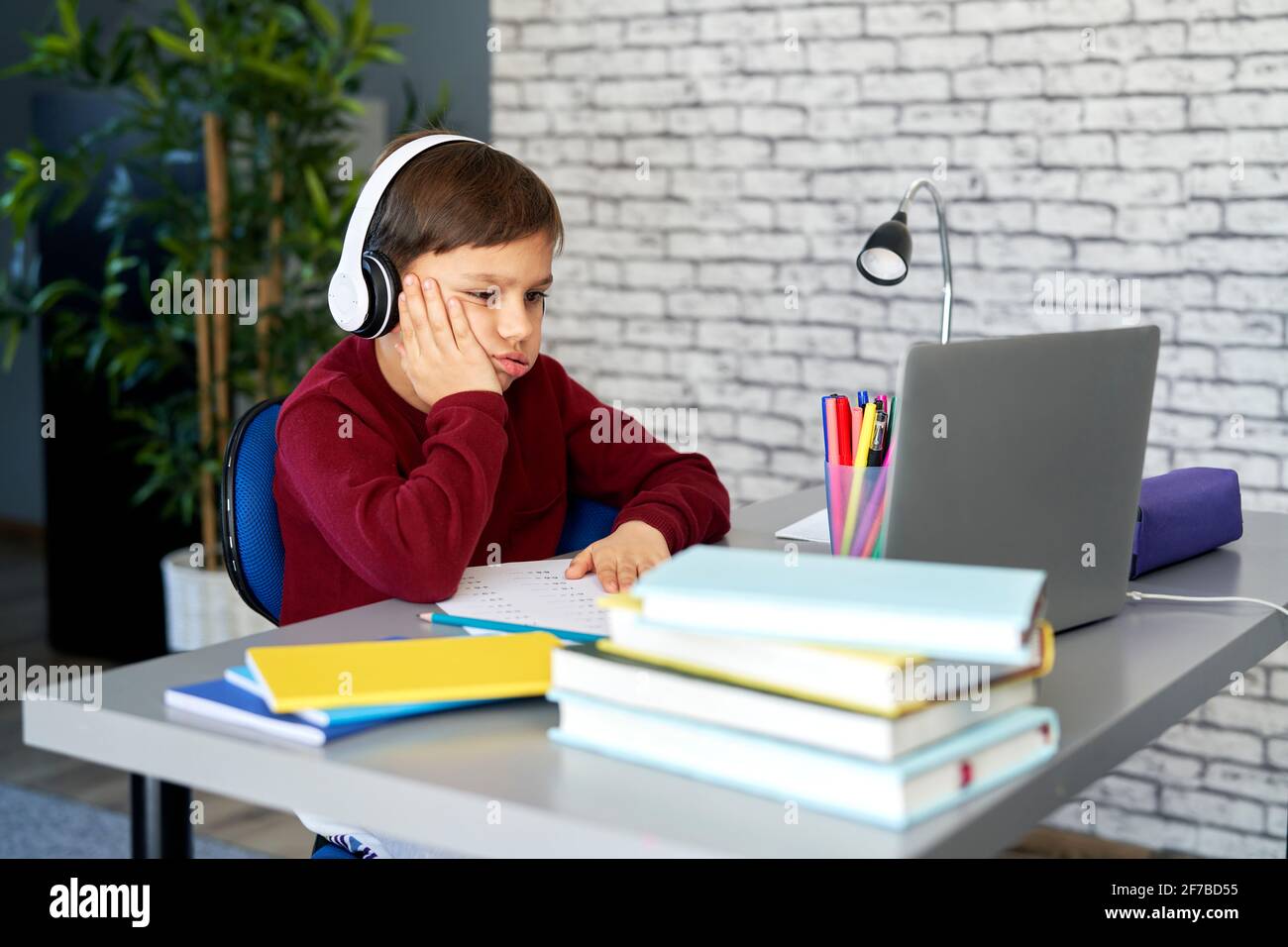 Müde Schuljunge sitzt während der Heimschooling Stockfoto