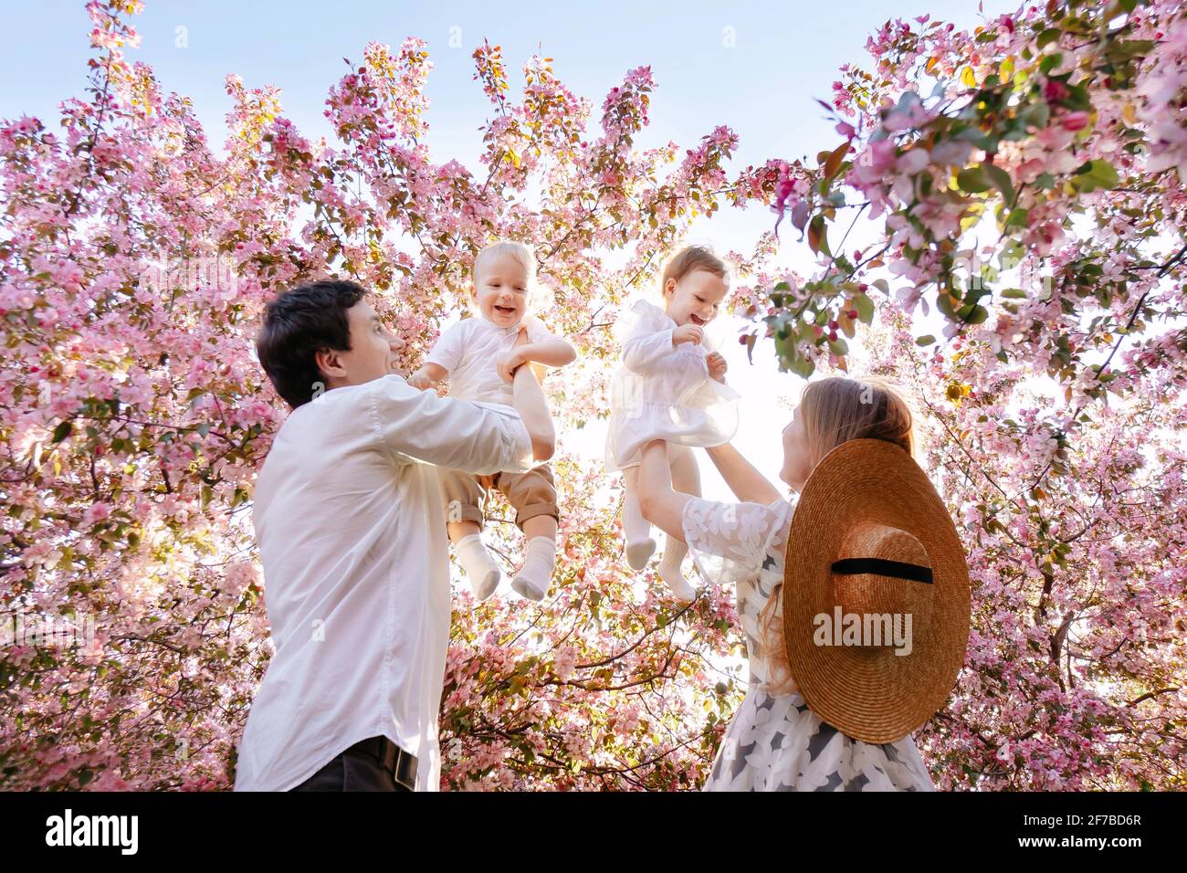 Im Sommer spielen Eltern mit Kindern im Garten vor der grünen Kulisse. Stockfoto