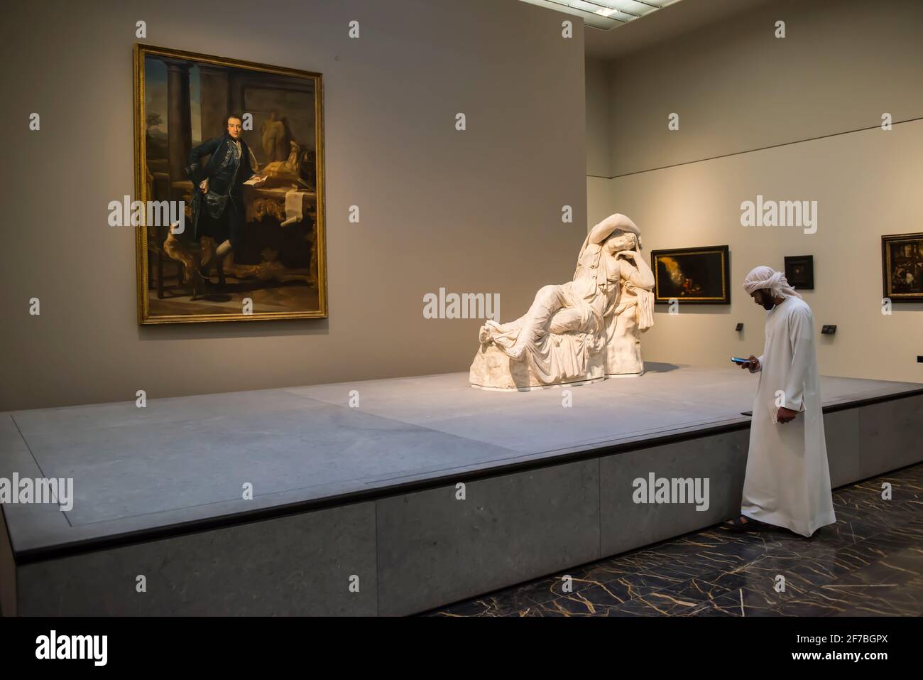 Arabischer Kunde schaut in einem Ausstellungsraum des Louvre auf sein Smartphone. Abu Dhabi, Vereinigte Arabische Emirate. Stockfoto