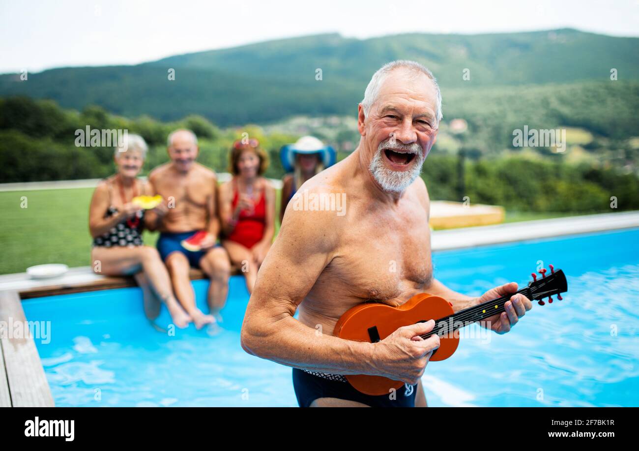 Gruppe von fröhlichen Senioren durch Schwimmbad im Freien im Hinterhof, Party-Konzept. Stockfoto
