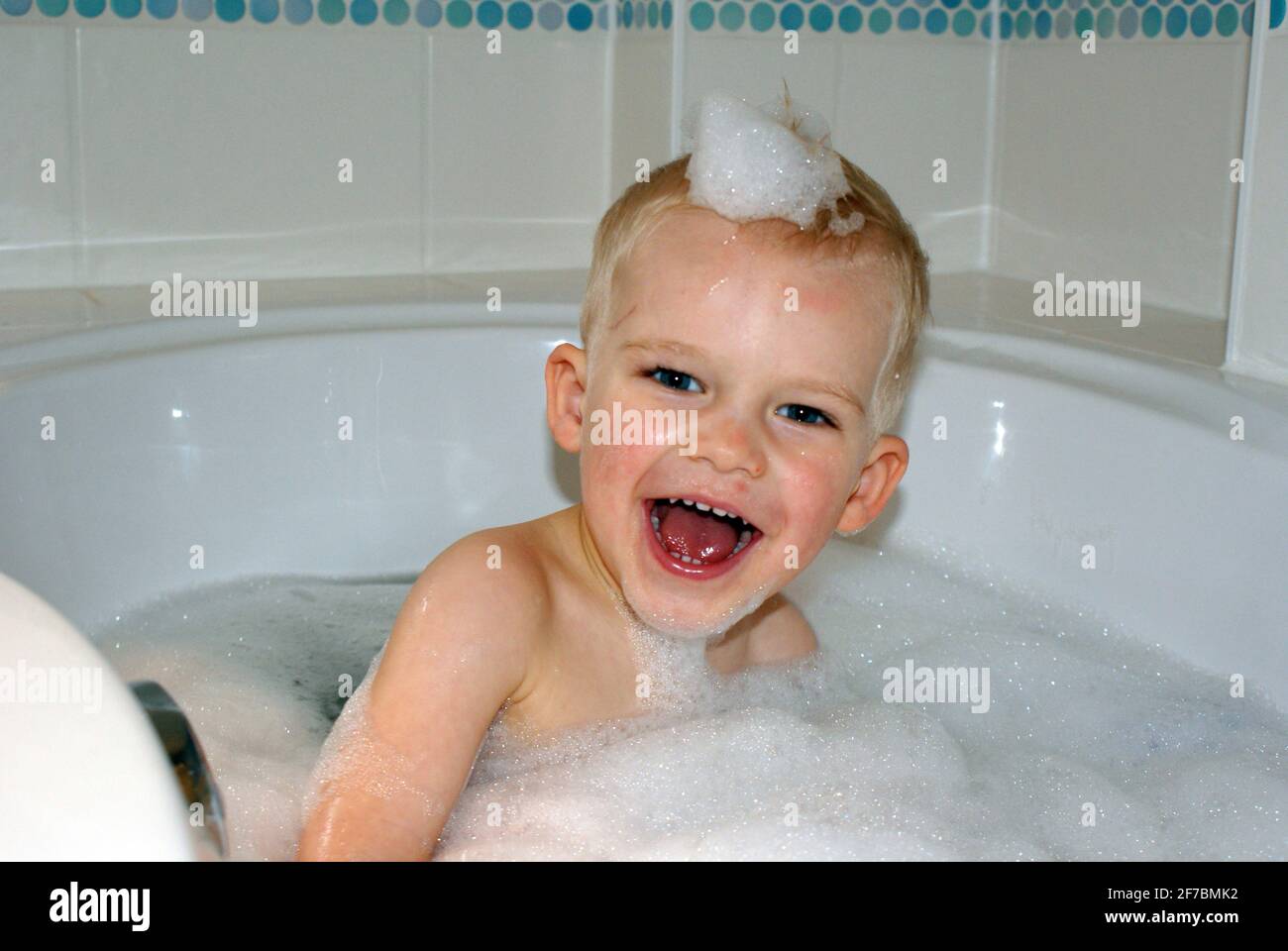 Drei Jahre alter Junge, der in einer Badewanne sitzt Stockfoto