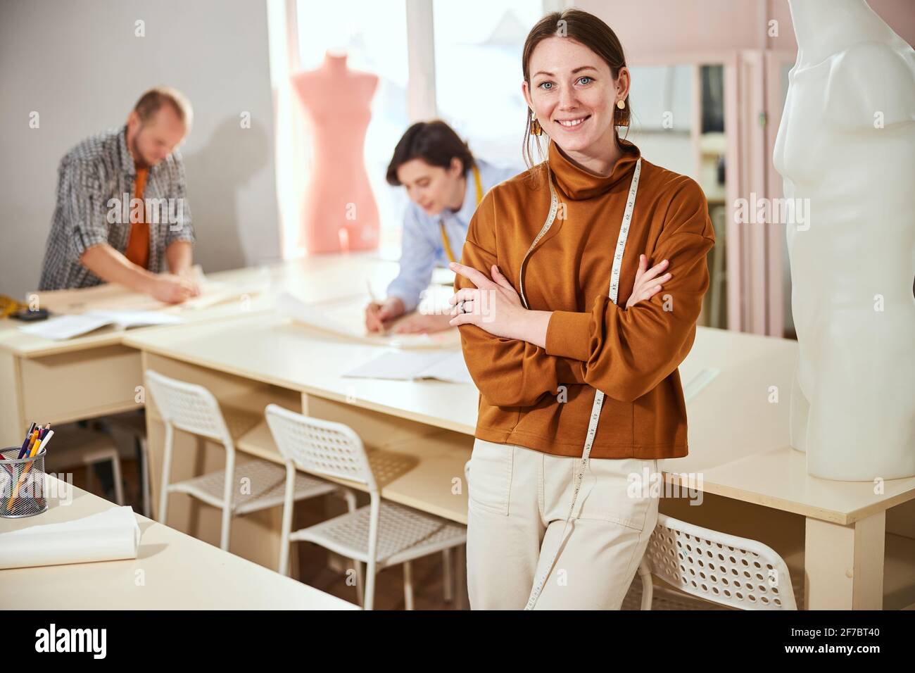 Modedesignerin lächelt vor zwei Arbeitskollegen Stockfoto