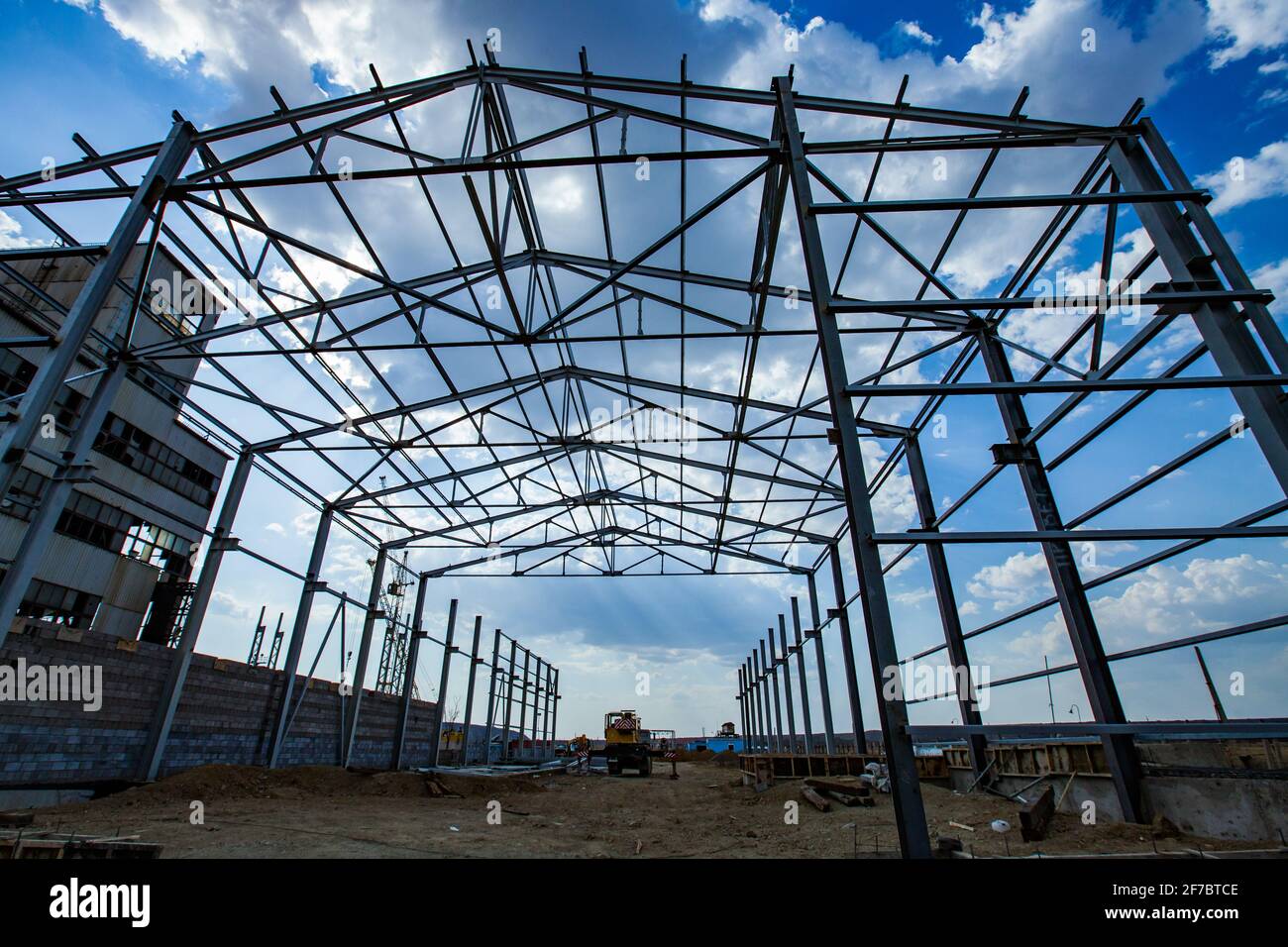 Bau eines neuen Industriegebäudes. Montage der Stahlkonstruktion. Blauer Himmel, Wolken. Stockfoto