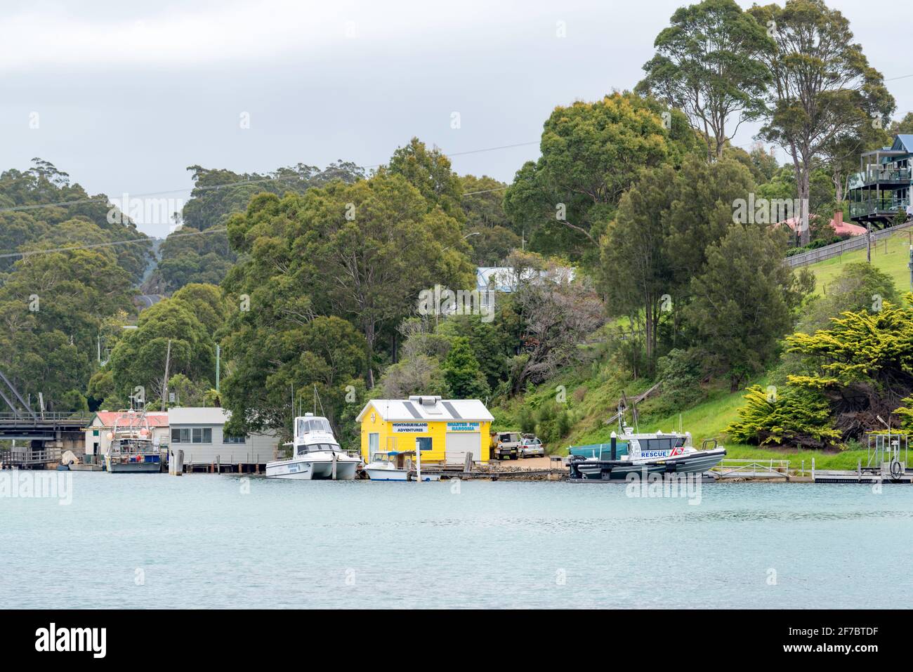 Eine Marine-Rettungsaktion in New South Wales, die in der Nähe eines historischen Bootes festgemacht ist Schuppen und die 1931 errichtete Stahltrassebrücke in Narooma An der Südküste von NSW Stockfoto Eine Marine-Rettungsaktion in New South Wales, die in der Nähe eines historischen Bootes festgemacht ist Schuppen und die 1931 errichtete Stahltrassebrücke in Narooma An der Südküste von NSW Stockfoto