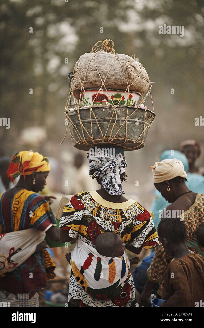 Afrikanische Frau trägt Last auf dem Kopf zum Markt in Djenne, Mali, Afrika. Frauen balancieren mehrere Töpfe auf ihren Köpfen. Stockfoto