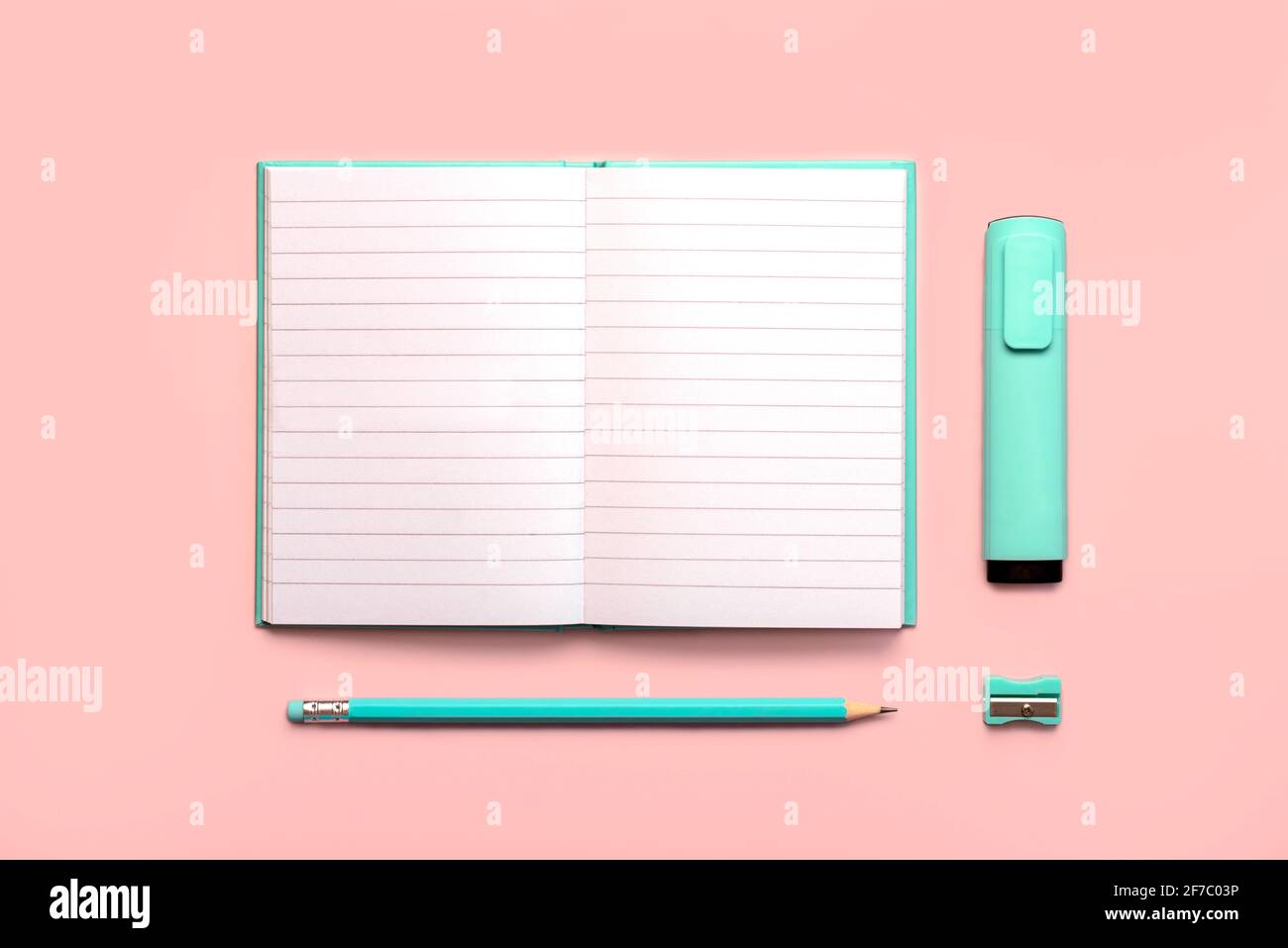 Offenes Tagebuch mit Kopierraum, blauem Stift, Textmarker blauem Marker und Blauer Bleistiftspitzer auf einem rosa Hintergrund.Arbeitsplatz Schreibtisch Stockfoto