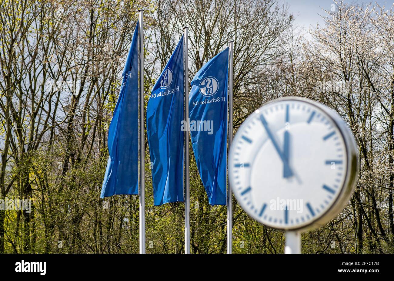 Gelsenkirchen, Deutschland. April 2021. Vor winkenden FC Schalke-Flaggen lautet die Zeit auf einer Uhr in den Vereinsbüros "fünf bis zwölf". Auf dem FC Schalke 04 wird heute der Konzernjahresbericht 2020 in einer Pressekonferenz veröffentlicht. Quelle: Guido Kirchner/dpa/Alamy Live News Stockfoto