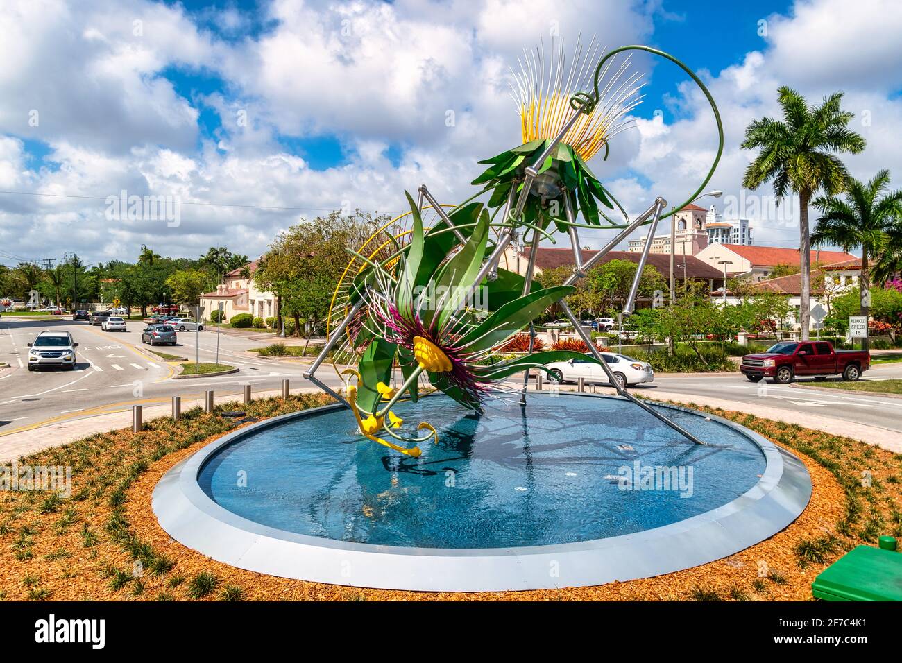Farbenfroher Springbrunnen mit floralen Skulpturen in einem Verkehrskreis von Miami, umgeben von Palmen und Vorstadthäusern, Miami, Florida, USA Stockfoto