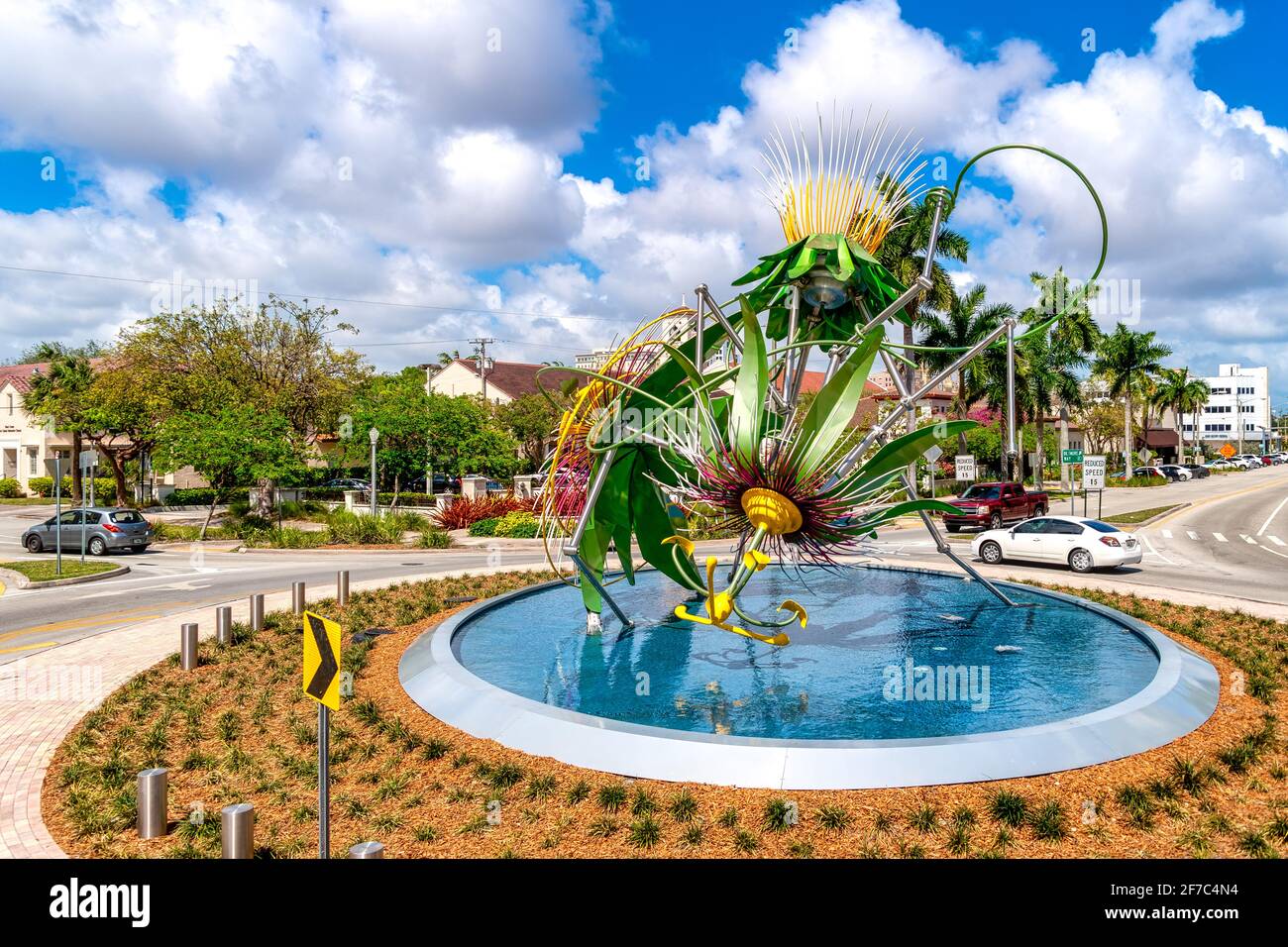 Farbenfroher Springbrunnen mit floralen Skulpturen in einem Verkehrskreis von Miami, umgeben von Palmen und Vorstadthäusern, Miami, Florida, USA Stockfoto