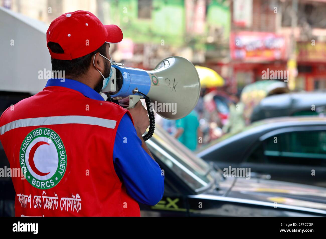 Dhaka, Bangladesch - 06. April 2021: Freiwillige der Red Crescent Society warnen Fußgänger vor dem Tragen von Masken im Maghbazar in Dhaka, dem zweiten d Stockfoto