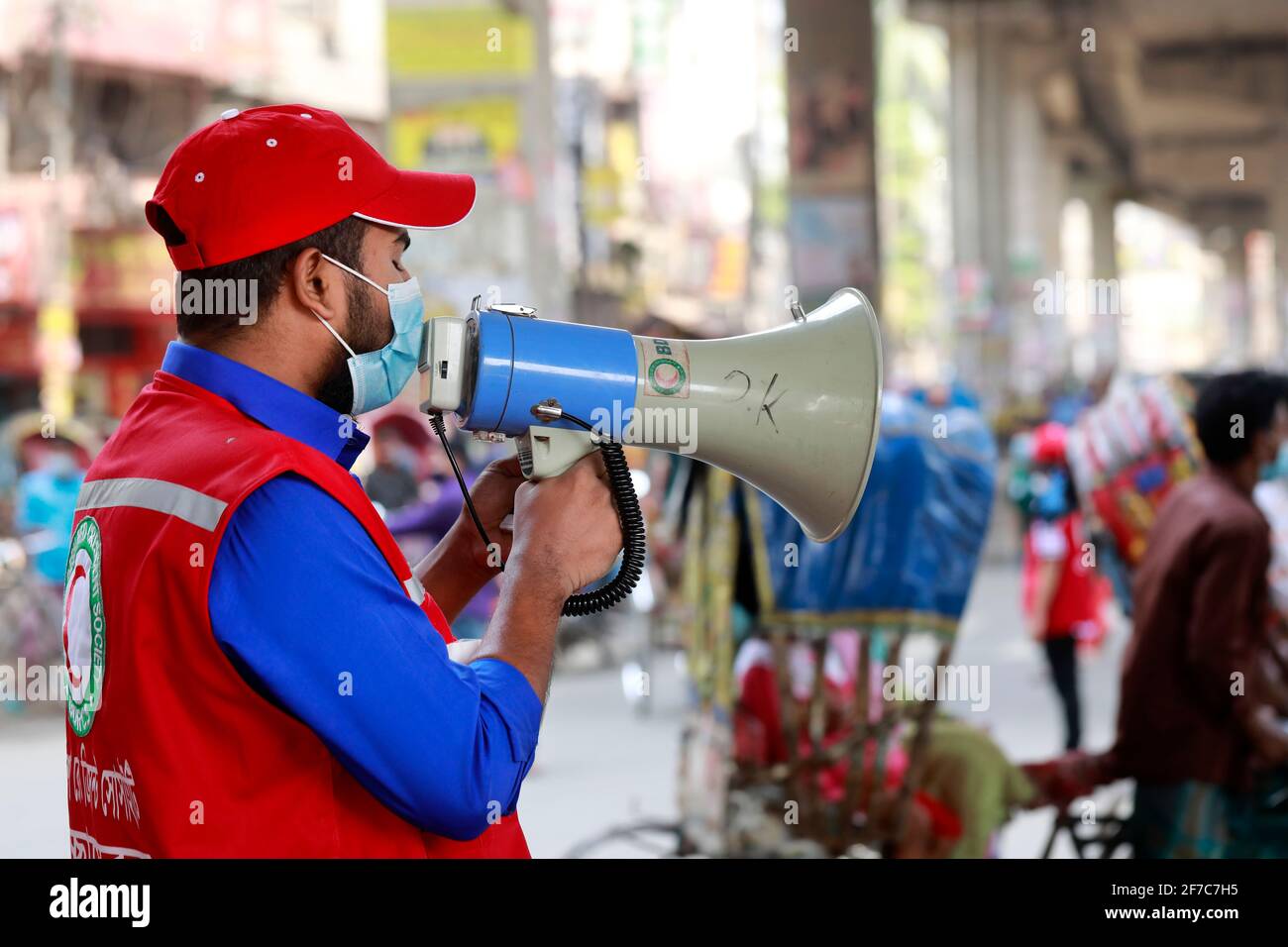 Dhaka, Bangladesch - 06. April 2021: Freiwillige der Red Crescent Society warnen Fußgänger vor dem Tragen von Masken im Maghbazar in Dhaka, dem zweiten d Stockfoto