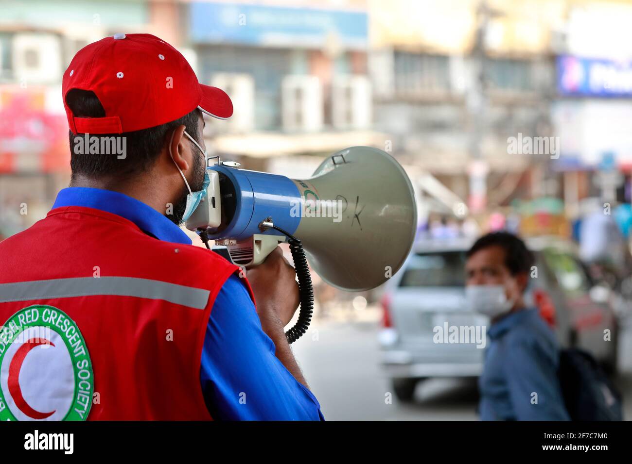 Dhaka, Bangladesch - 06. April 2021: Freiwillige der Red Crescent Society warnen Fußgänger vor dem Tragen von Masken im Maghbazar in Dhaka, dem zweiten d Stockfoto