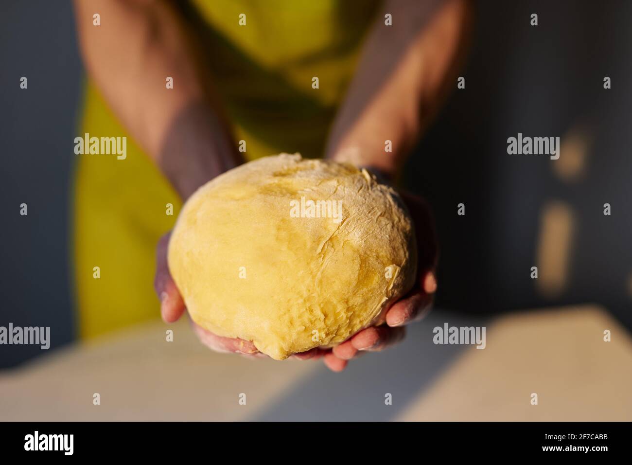 Der Chefbäcker in grüner Schürze hält in den Händen einen Teig, der für Brot,  Pizza oder Kuchen zubereitet wird. Hausgemachtes Gebäck backen, Ostergebäck  vorbereiten oder leckeres Cookie-Konzept. Hochwertige Fotos Stockfotografie  - Alamy