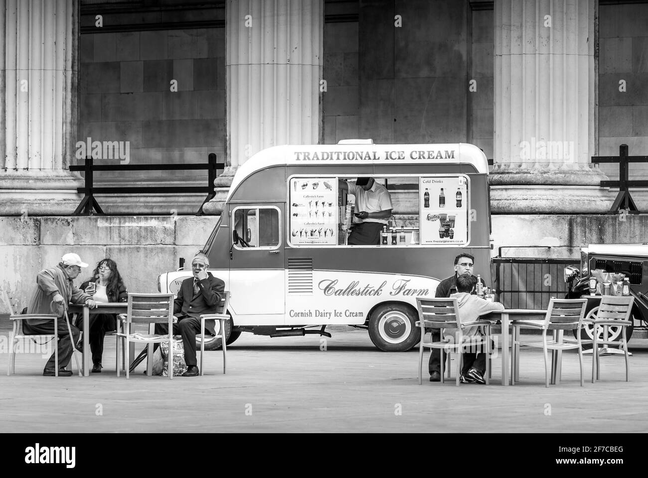 Schwarz-weiß-Szene mit traditionellem Eiswagen und Menschen, die draußen in London sitzen Stockfoto