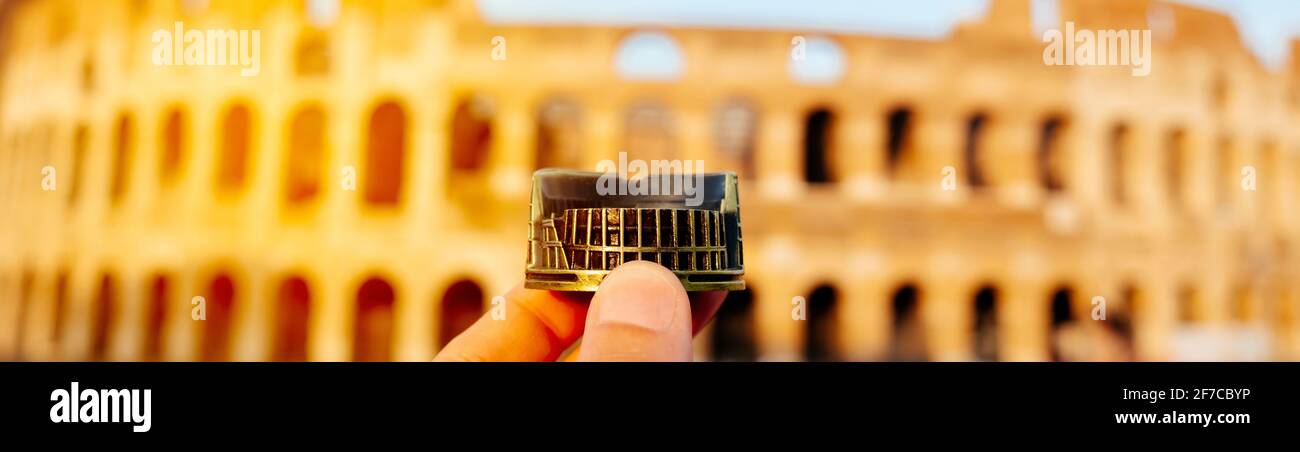 Ein junger Kaukasusmann hält eine Miniatur des Kolosseums in Rom, Italien, vor dem berühmten Wahrzeichen in einem Panoramafenster, das als Webbanner verwendet werden kann Stockfoto