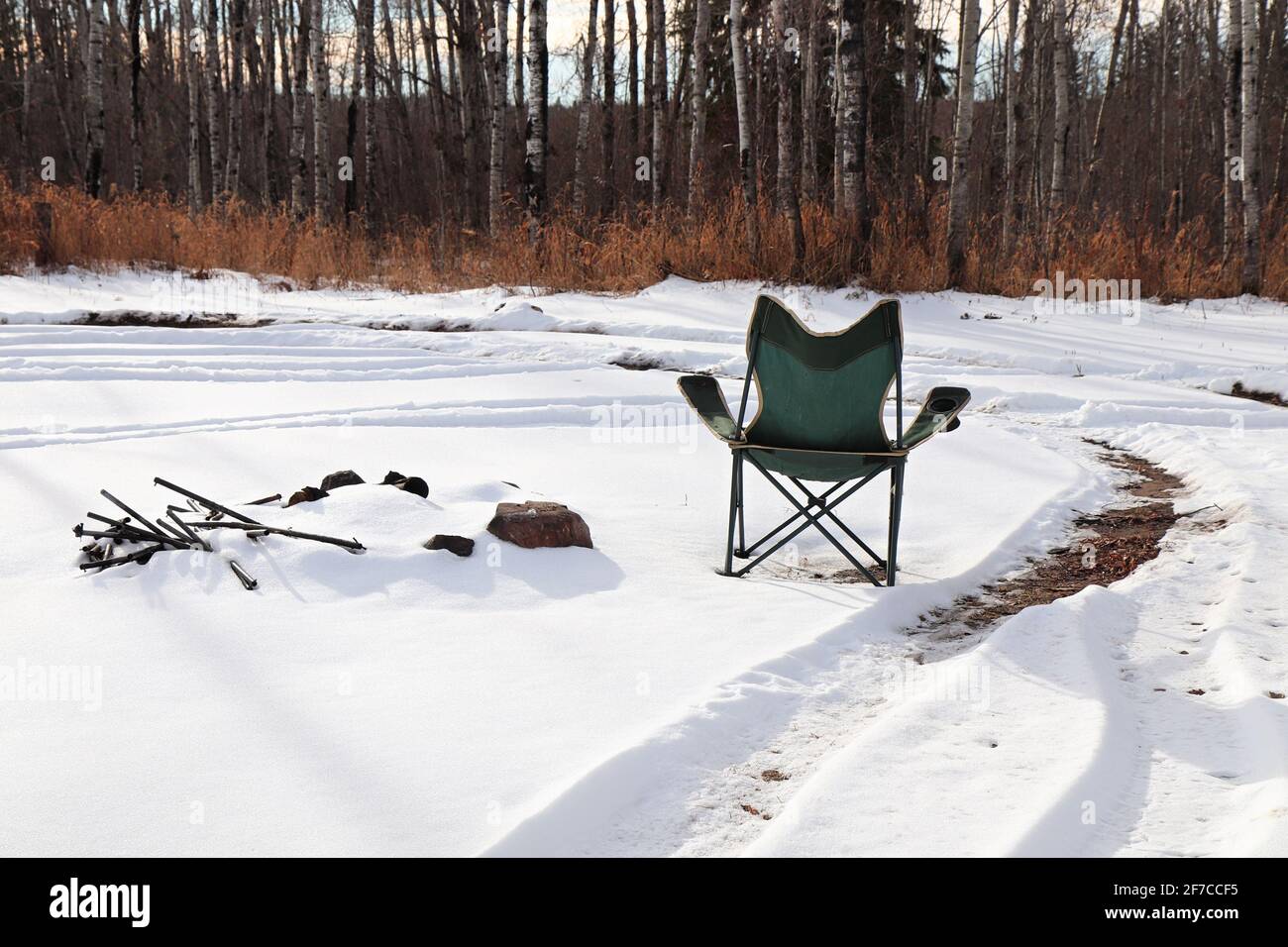 Ein Campingstuhl im Schnee neben einer überdachten Feuerstelle Stockfoto