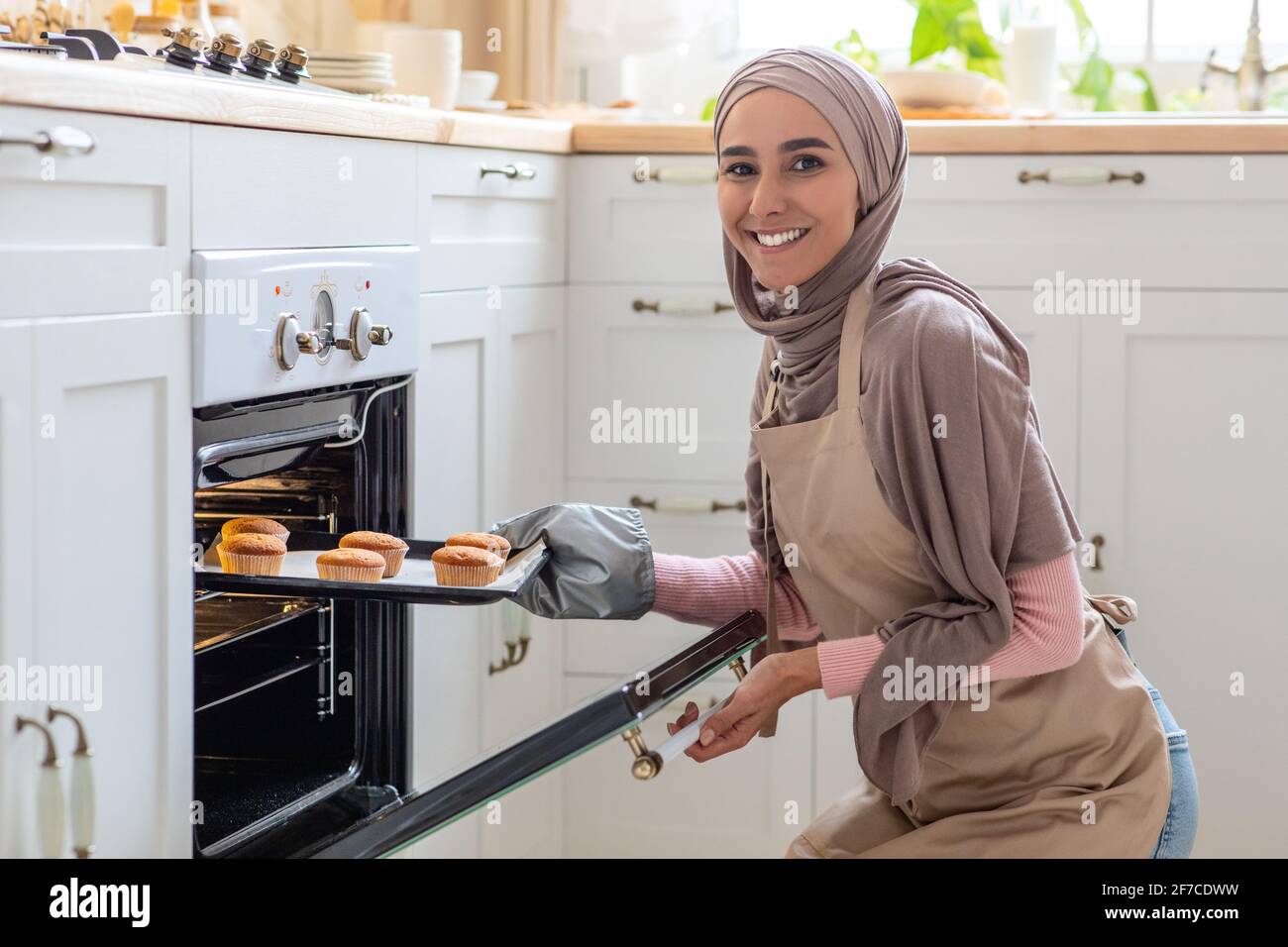 Muslimische Hausfrau. Porträt Einer Lächelnden Frau Im Hijab Baking In Kitchen Stockfoto