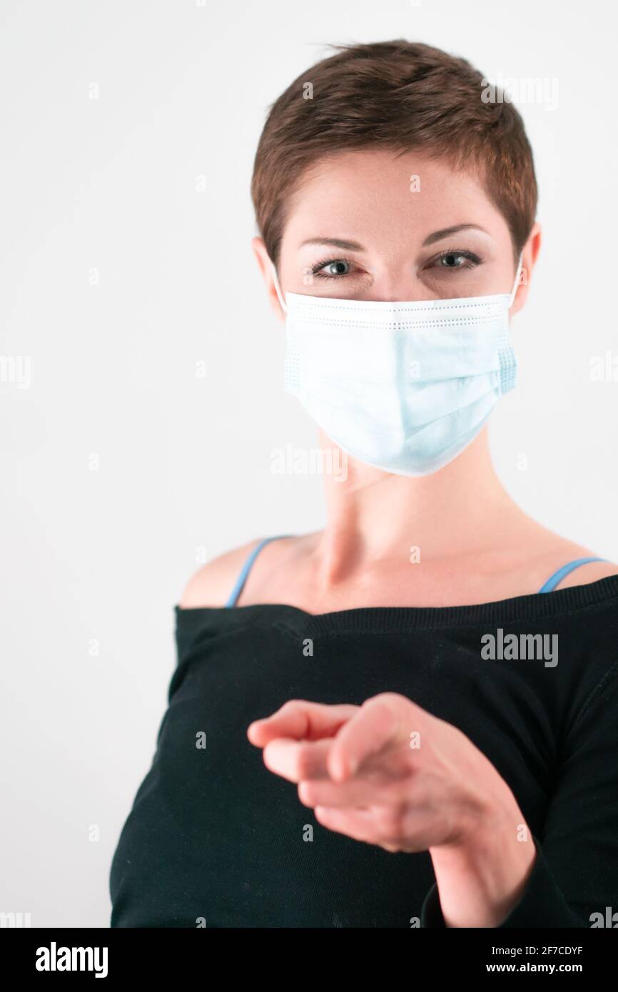 Schöne Frau mit kurzen Haaren trägt eine Gesichtsmaske in einer Geste, die ich will, DASS DU... Leben in Quarantäne. Umgang mit Einschränkungen des Coronavirus. Life du Stockfoto