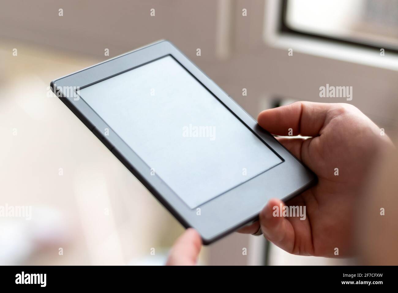Männliche Hände mit modernem E-Book mit leerem Bildschirm Nahaufnahme. Lesen zu Hause auf dem Balkon mit einem Taschenleser Stockfoto