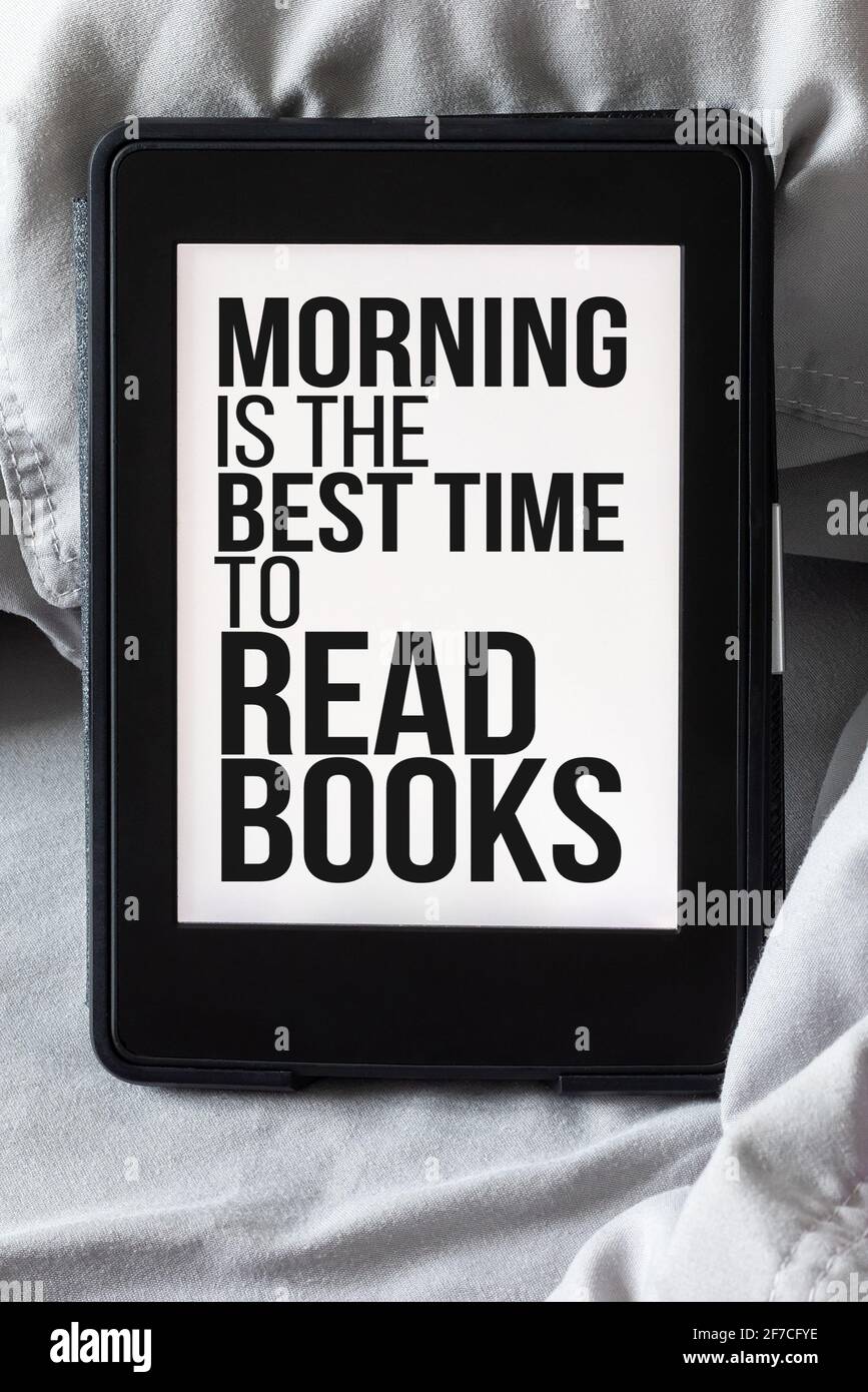 Modernes elektronisches E-Reader-Buch mit Text auf dem Bildschirm - morgens ist die beste Zeit, um Bücher zu lesen - auf grauem und purpurem Bett. Tablet mit Zitat zum Lesen Stockfoto