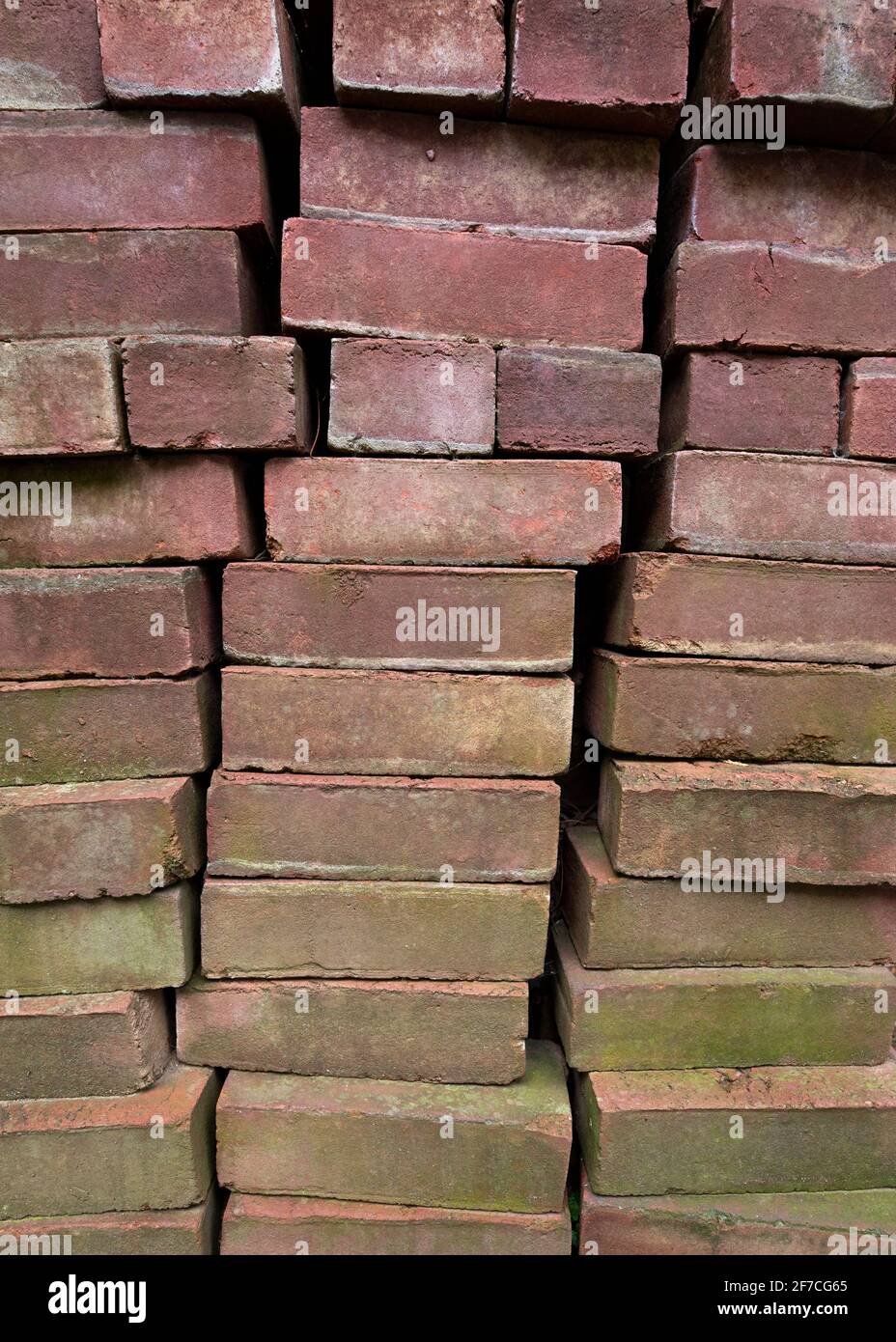 Ziegelsteine, Schieferplatten und andere Baumaterialien werden am frühen Frühling am Apriltag in einem launischen, abstrakten, grunge Hintergrundbild gestapelt gesehen Stockfoto