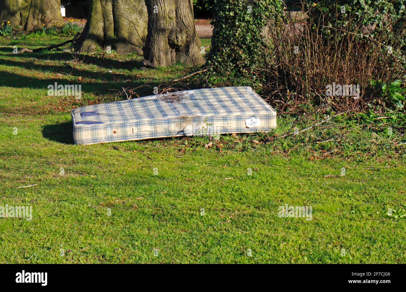 Eine Matratze, die auf einem kleinen Grün in einem Wohngebiet des Borough of Hellesdon, Norfolk, England, Vereinigtes Königreich, mit Fliegenspitzen aufliegt. Stockfoto