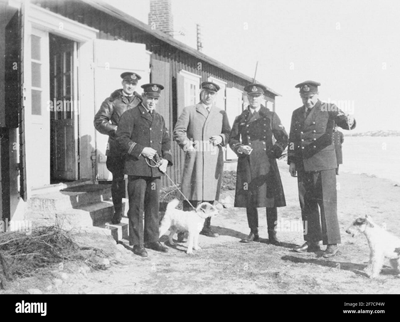 Fünf Offiziere und zwei Hunde posieren vor einem Haus. Fünf Offiziere und zwei Hunde posieren vor einem Haus. Stockfoto