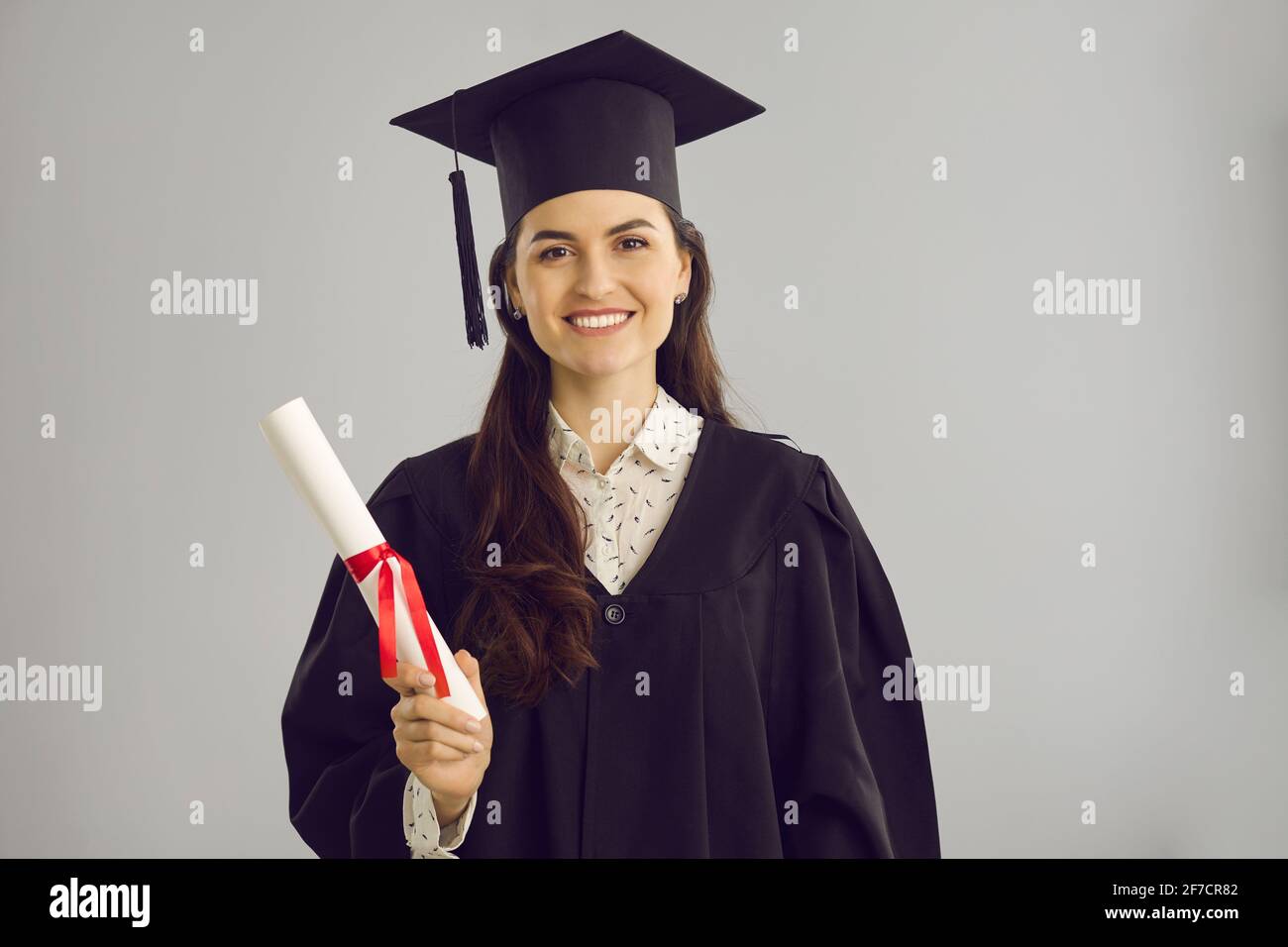 Studentin in akademischem Kleid und Hut mit einem Hochschul- oder Akademiezertifikat. Stockfoto
