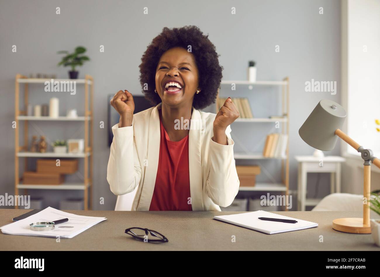 Glückliche Geschäftsfrau Büroangestellte Gefühl Aufregung Anheben Faust sitzen an Schreibtisch Stockfoto