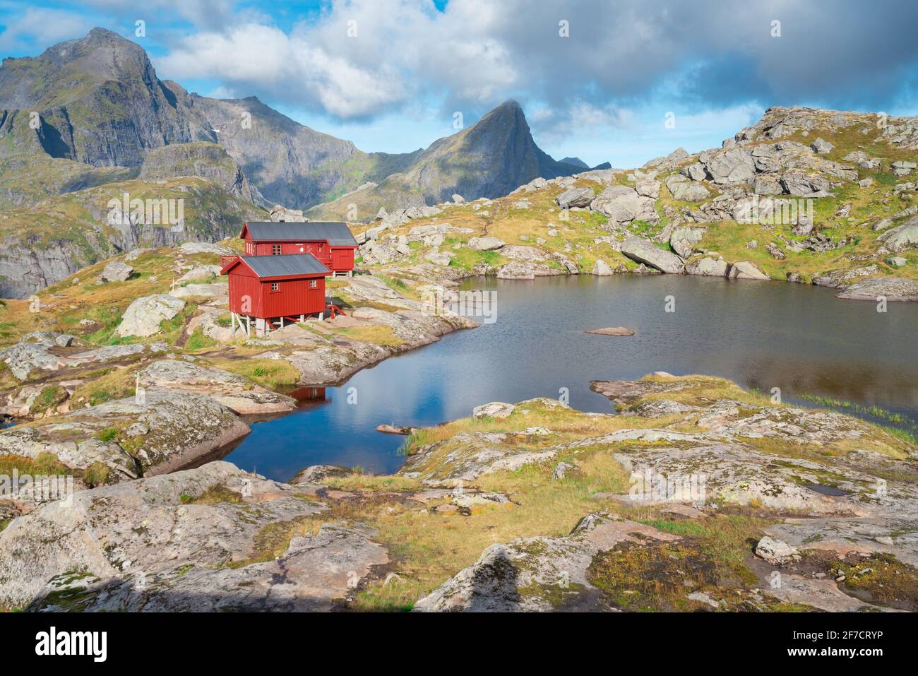 Steile Berge der Lofoten Island an einem sonnigen arktischen Tag. Hermannsdalstinden Gipfel und rote Holzhütte der Munkebu Hütte. Wandern Berge von Lofoten, NOR Stockfoto