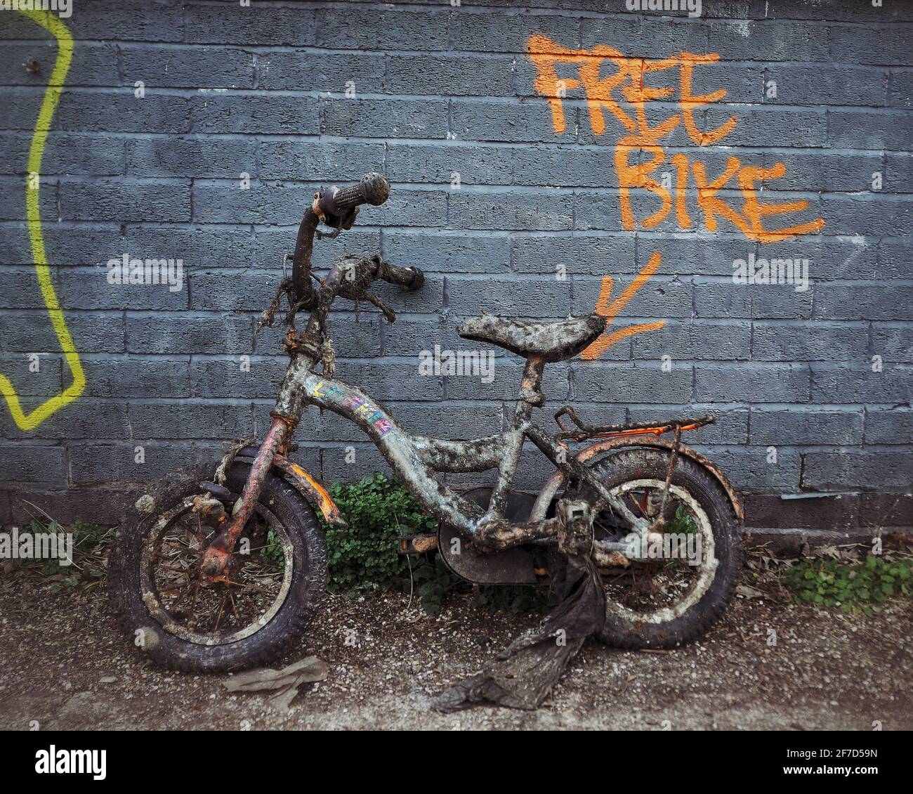 Ein korrodiertes Kinderfahrrad, das aus dem Regent’s Canal geborgen wurde und an einer Wand mit der Aufschrift „Free Bike“ an der Wand gelehnt war Stockfoto