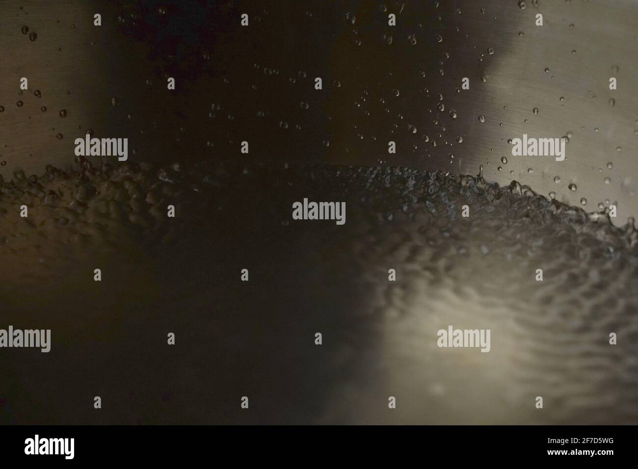 Tibetische Klangschale voller Wasser, Nahaufnahme von Wassertropfen, Klangheilungsinstrument Stockfoto