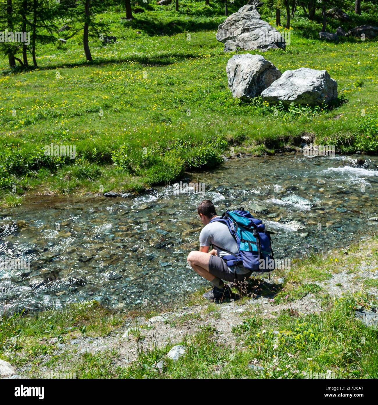 Wanderer erfrischt sich mit dem kühlen Wasser eines Bergbaches. Stockfoto