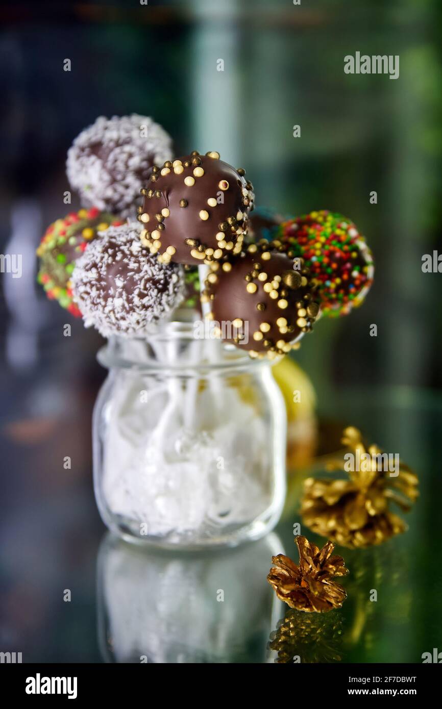Verschiedene bunte Schokoladenkuchen knallt in einem transparenten Glas. Nahaufnahme, selektiver Fokus Stockfoto