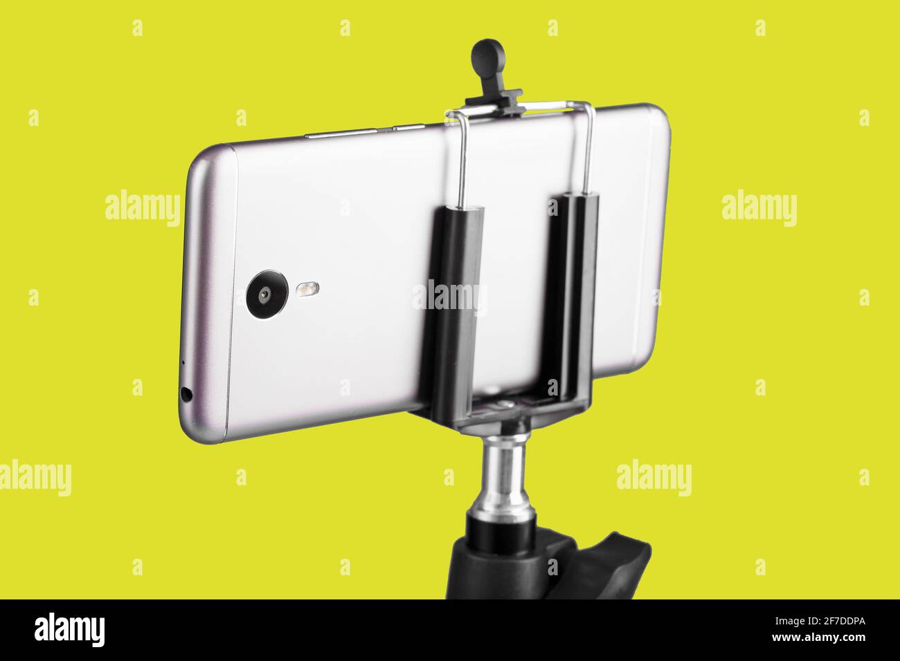 Smartphone auf einem Stativ auf gelbem Hintergrund befestigt. Selfie- und Blogging-Konzept Stockfoto