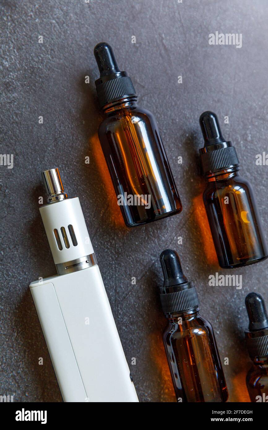 Dampfgerät E-Zigarette elektronische Zigarette und flüssige Flaschen auf dunklen schwarzen Stein Schiefer Hintergrund. Dampfvorrichtung für alternatives Rauchen. Dampfende sh Stockfoto
