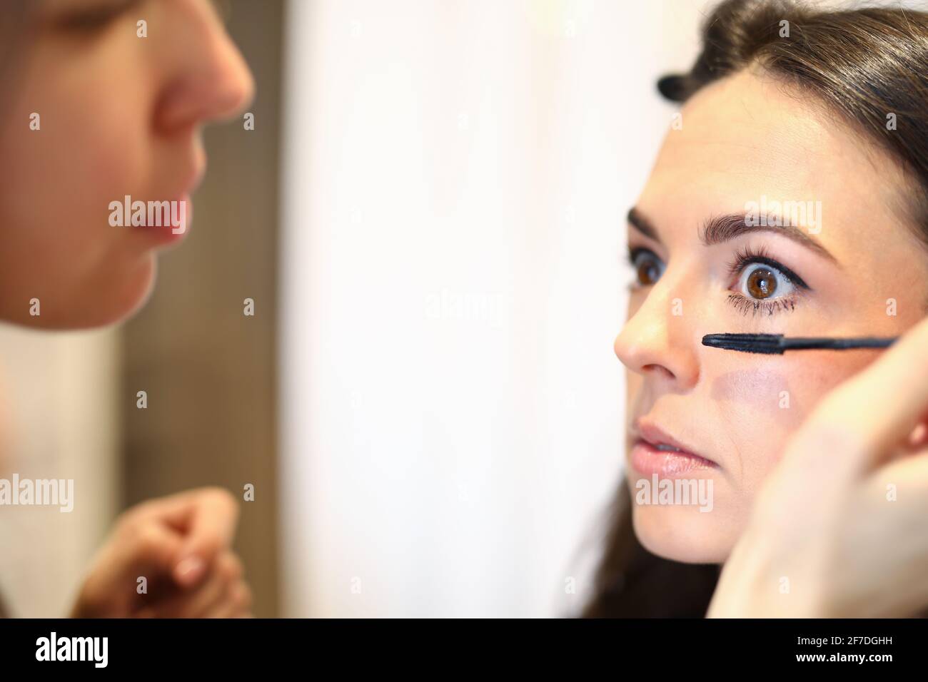 Portrait eines professionellen mua-Meisters, der Mascara auf die Wimpern des Kunden auftragene Stockfoto