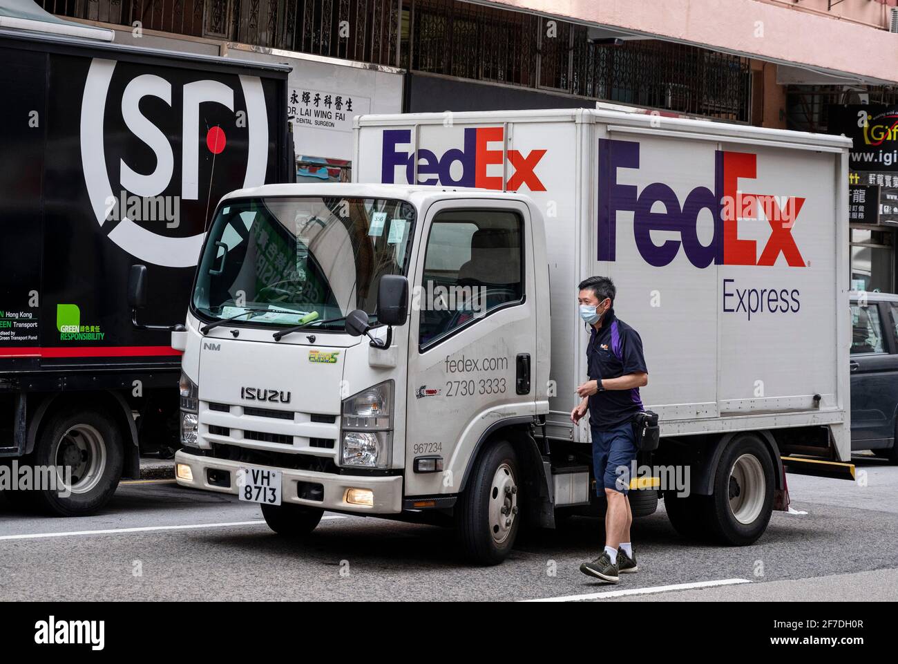 Hongkong, China. April 2021. Ein Mitarbeiter der American FedEx Express Lieferung wird gesehen, wie er in den LKW kommt, da die Lastwagen des chinesischen multinationalen Lieferdienstes und Logistikunternehmens SF Express auf der Straße in Hongkong stationiert sind. (Foto von Budrul Chukrut/SOPA Images/Sipa USA) Quelle: SIPA USA/Alamy Live News Stockfoto