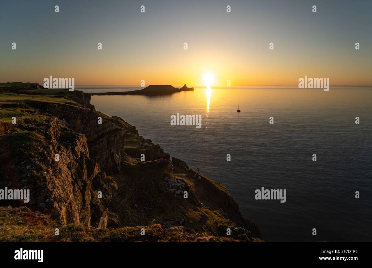 Worm's Head Rhossili Bay bei Sonnenuntergang und ein Einzelboot, Gower Peninsula, South Wales, Großbritannien Stockfoto