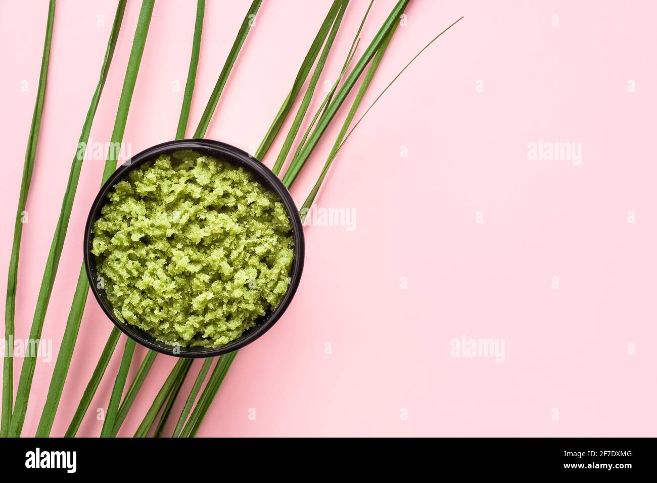 Hausgemachtes grünes Körperpeeling in einer Schüssel auf einem rosa Hintergrund. Draufsicht, Platz für Text kopieren. SPA-Konzept. Selektiver Fokus Stockfoto