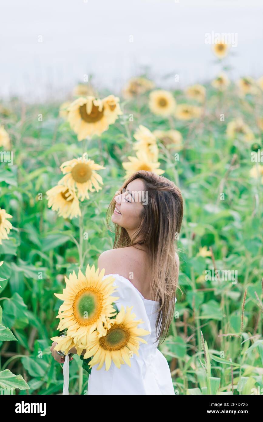 Schönheit fröhliche junge Frau mit Sonnenblume genießen die Natur und lachen auf dem Sommerfeld. Sonnenstrahlen, Sonnenstrahlen, leuchtende Sonne. Stockfoto