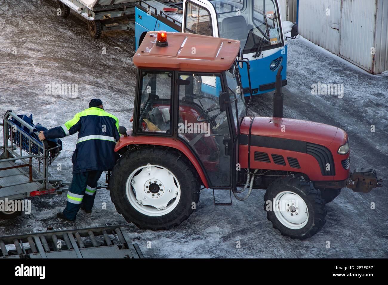 Ein Bodenpersonal des Flughafens manipuliert mit einem Trolley für den Anschluss am Traktor. Stockfoto