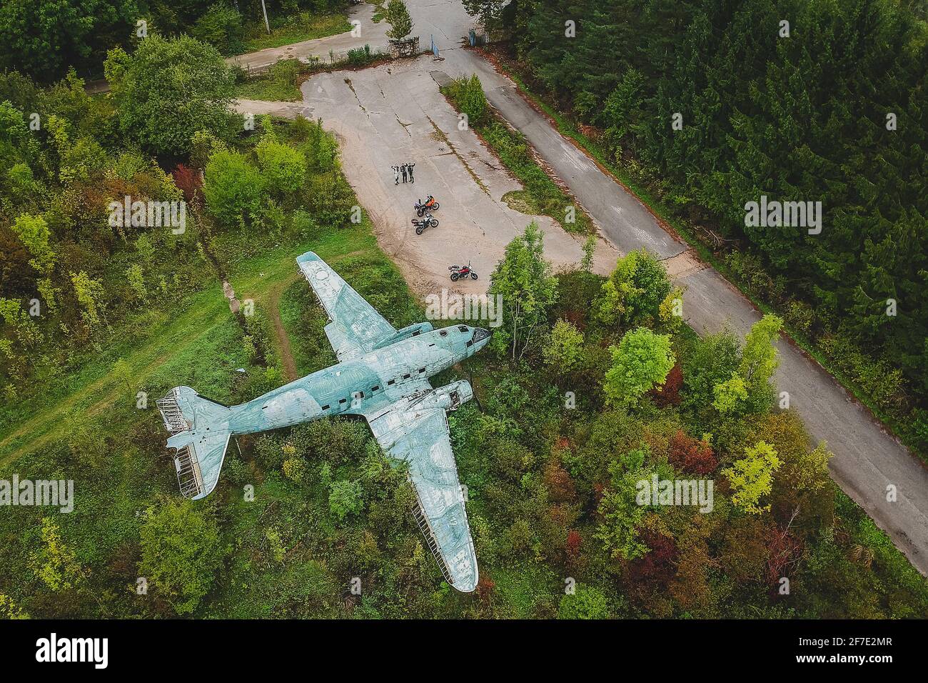 Ein Drohnenschuss eines verlassenen Flugzeugs und einiger Motorradfahrer auf dem ehemaligen unterirdischen Flugplatz in Zeljava, Kroatien. Stockfoto